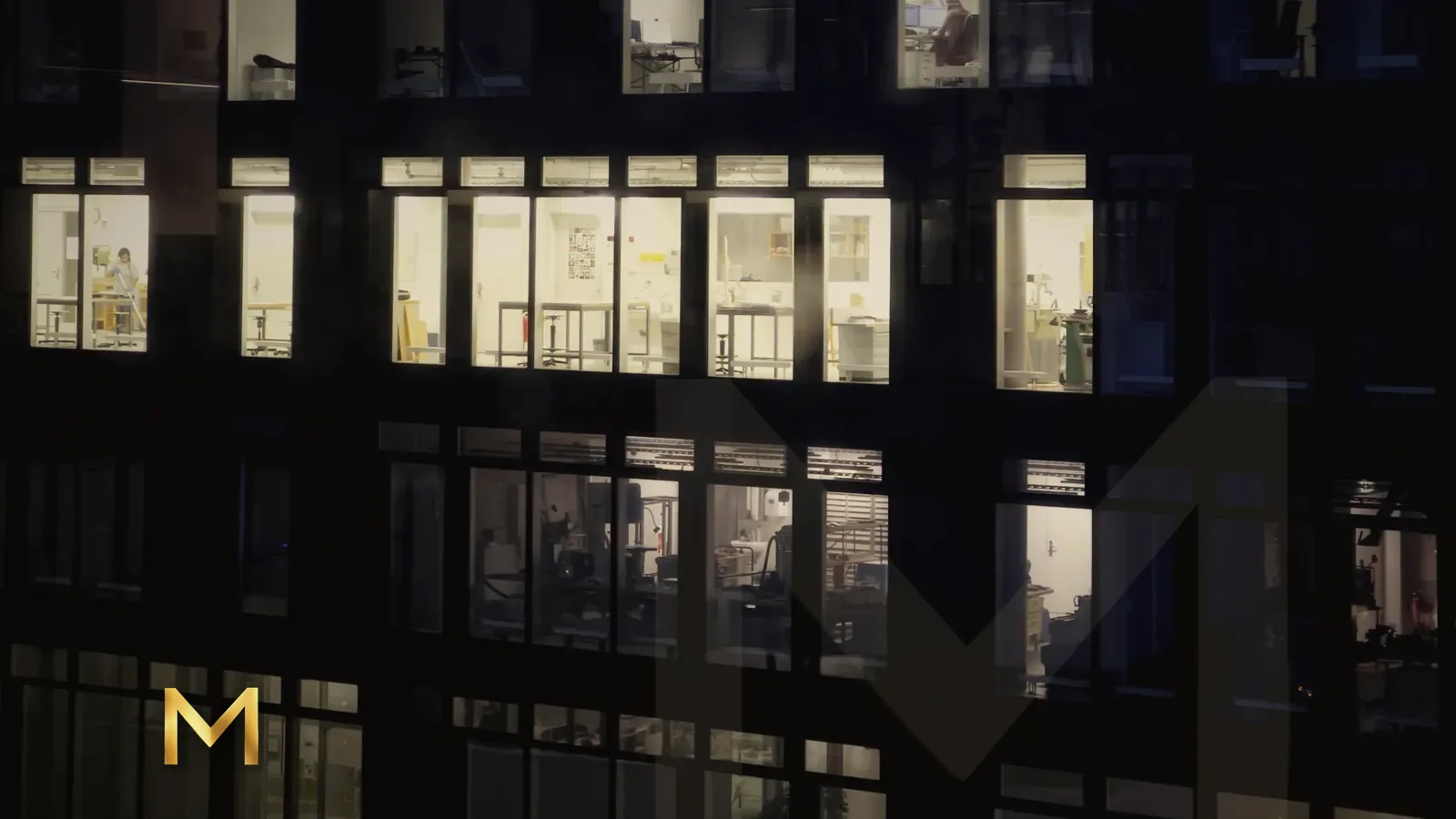 Rows of lit office windows in a dark building at night