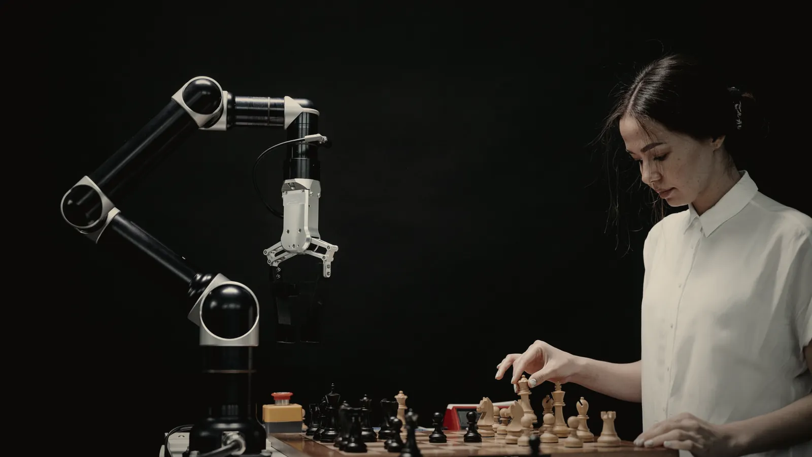 A robotic arm and a woman playing chess across the same board