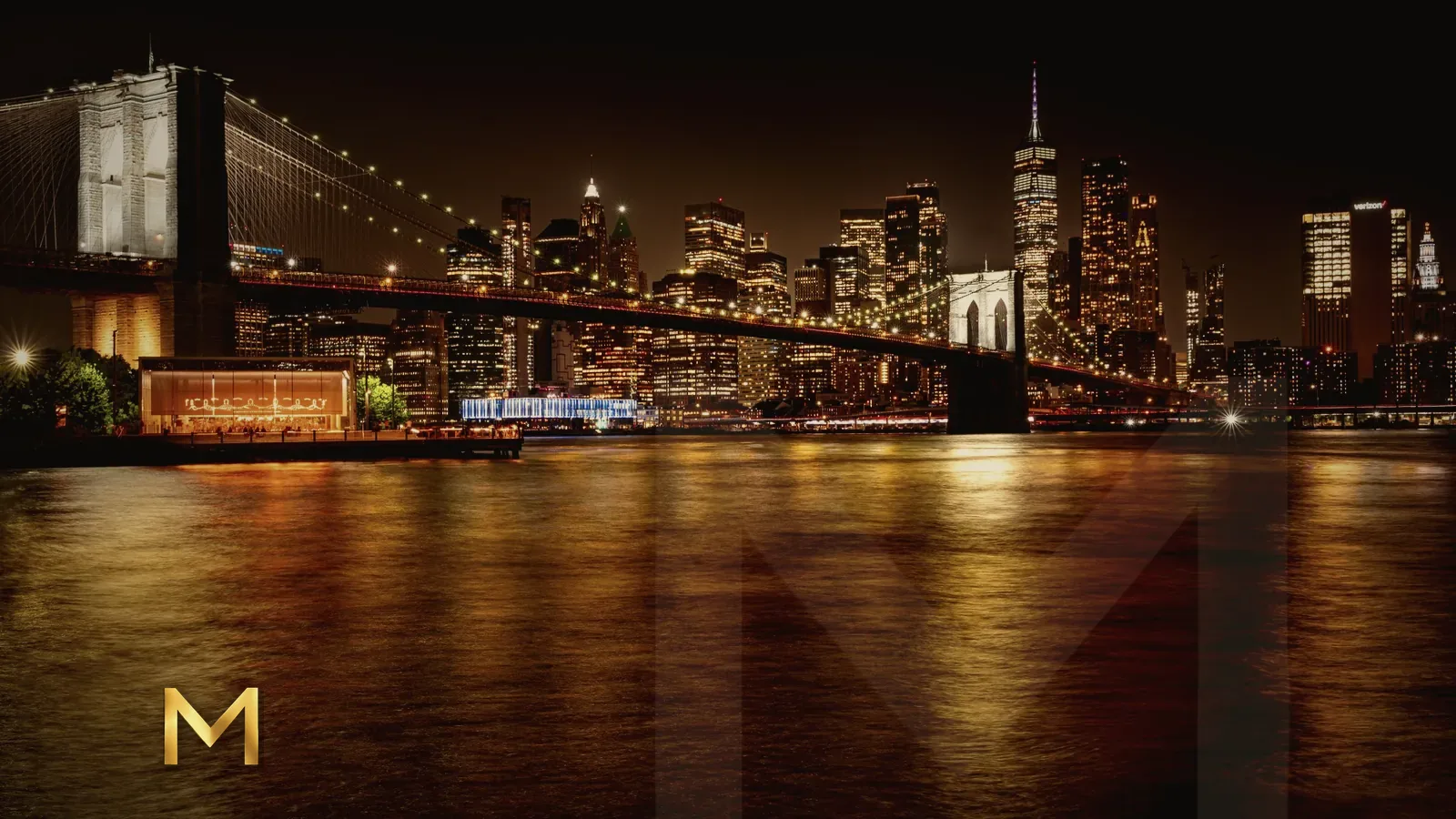The Brooklyn Bridge and the Manhattan skyline lit up at night above the East River